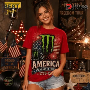 Monster Energy 1776-2026 America Freedom Anniversary T-Shirt 4 Woman wearing red Monster Energy graphic t-shirt featuring American flag, fireworks, and 1776-2026 text with urban decor.!