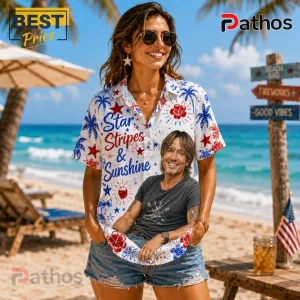 Woman wearing white short-sleeve shirt with red, white, and blue star, hibiscus, and text print on a tropical beach.!
