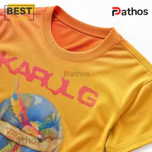 Karol G Tropitour Viajando Por El Mundo Tour Graphic T-Shirt 5 Mustard yellow short-sleeve crewneck t-shirt featuring a parrot, globe graphic, and the red text KAROL G and TROPICOOR.!
