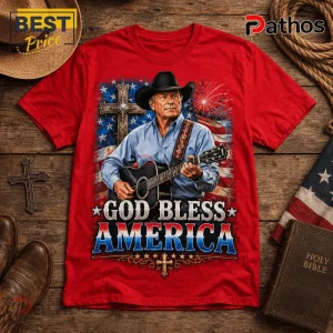 Red cotton t-shirt featuring a cowboy playing acoustic guitar, a cross, fireworks, and the text God Bless America.!