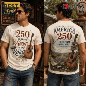 Man wearing white graphic t-shirt featuring acoustic guitar, harmonica, highway, and America 250 text design on cream fabric.!