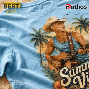 Light blue t-shirt with a graphic of a muscular man wearing a cowboy hat and playing guitar on a tropical beach.!