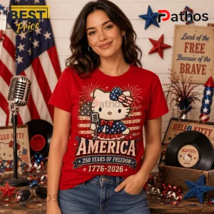Hello Kitty x America 250 Years of Freedom 1776-2026 Patriotic T-Shirt 4 Woman wearing a red t-shirt with Hello Kitty holding a microphone, stars and stripes pattern, and America 1776-2026 text.!