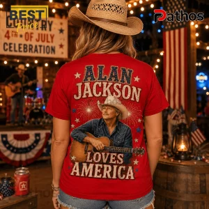 Red graphic t-shirt featuring Alan Jackson, an acoustic guitar, fireworks, and text reading Alan Jackson Loves America.!