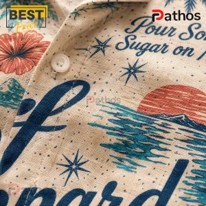 Beige linen button-down shirt featuring a nautical sunset print, blue script text, and red tropical flower patterns.!