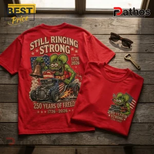 Red cotton t-shirt featuring a green cartoon mouse driving a hot rod with a US flag, bell, and 1776-2026 anniversary text.!