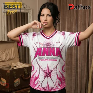 Woman wearing white V-neck jersey with pink flames, chains, stars, and Anna Million Dollar Babe Tour 2026 text graphics.!
