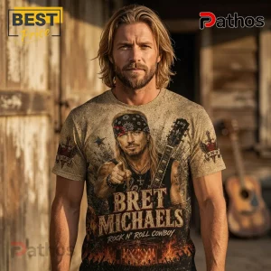 Bret Michaels Rock N Roll Cowboy Retro Casual Apparel T-Shirt 1 Man wearing a tan crew-neck t-shirt featuring a Bret Michaels portrait, guitar, bandana, and Rock N' Roll Cowboy text print.!