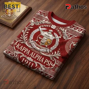 Kappa Alpha Psi fraternity t-shirt in crimson red with white greek patterns, crest, and the year 1911 on a wooden surface.!