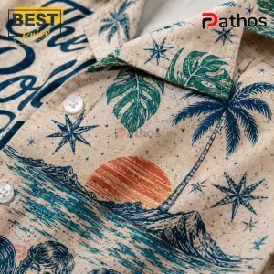 Beige button-up shirt featuring blue palm trees, monstera leaves, nautical stars, and an orange sunset graphic pattern.!