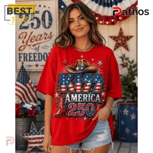 Woman wearing a red t-shirt with patriotic KISS America 250 graphic featuring a cowboy hat, stars, and red cowboy boot.!