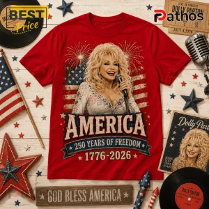 Dolly Parton x USA 250 Years of Freedom Anniversary T-Shirt 2 Red cotton t-shirt featuring Dolly Parton, a US flag background, text America 250 Years of Freedom and 1776-2026 graphic.!