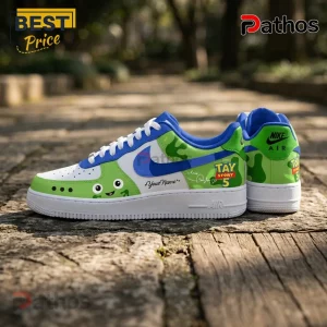 Custom Nike Air Force 1 sneakers with green alien character, blue swoosh, white laces, and Tay Story 5 text on stone path.!