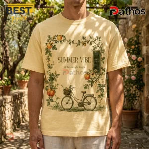 Pale yellow t-shirt with botanical illustration of a bicycle, fruit vines, and text stating Summer Vibe and sunlight.!