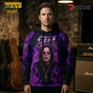 Ozzy Osbourne Signature Tribute 1948-2025 Hoodie 1 Man wearing a purple hoodie featuring an Ozzy Osbourne portrait, black smoke patterns, and a cross necklace graphic.!