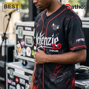 Man wearing a black and red custom baseball jersey featuring McKenzie 2.0 Tour text and splattered paint graphics.!