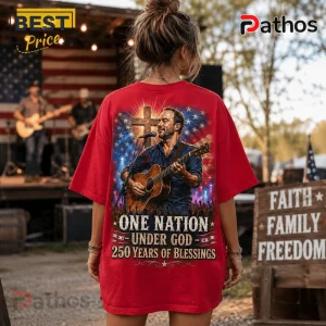 Red graphic t-shirt featuring a male singer with guitar, a cross, American flag motif, and text One Nation Under God.!