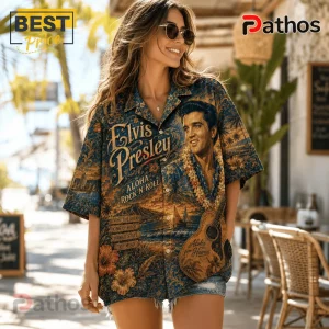 Woman wearing a blue Hawaiian shirt featuring an Elvis Presley portrait, guitar graphic, and tropical floral patterns.!