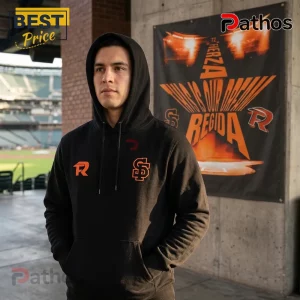 Man wearing black hoodie with orange R and SF logos standing in front of a banner with a large orange star graphic.!