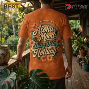 Back view of a person wearing an orange crewneck shirt with hibiscus flowers, palm trees, and text Aloha Mood Busy Nothing.!