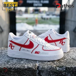 BC Lions Personalized Pacific Frost Custom AIr Force 1 Sneakers 3 Custom white leather sneakers with red Nike swoosh, BC Lions logo, and Your Name text on a snowy concrete ledge background.!