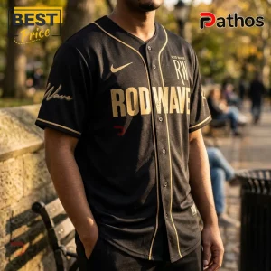 Black baseball jersey with gold piping and Rod Wave text across the chest and sleeve on a male model.!