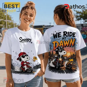 White crewneck t-shirt featuring Snoopy and Woodstock riding motorcycles with We Ride At Dawn text on the back.!