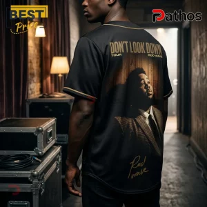 Black baseball jersey with Don't Look Down Rod Wave tour text, graphic portrait, and gold trim worn by a man in a studio.!