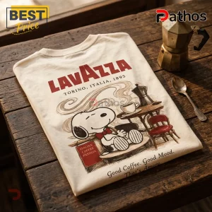 Off-white t-shirt featuring Snoopy drinking coffee, Lavazza logo, and text reading Italian Coffee Passion on wooden table.!