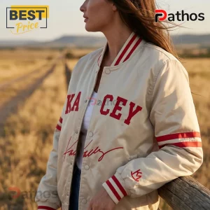 Cream satin bomber jacket with red KACEY lettering and stripes on sleeves worn by a woman in a field.!