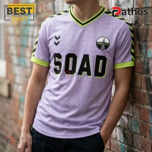 Lavender V-neck soccer jersey featuring black SOAD lettering, Toxicity crest, and lime green trim against a brick wall.!