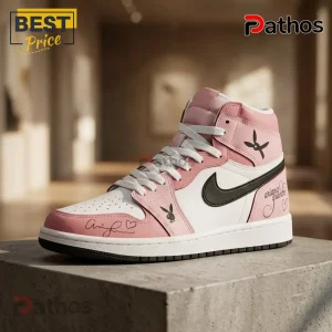 Ariana Grande Eternal Sunshine Tour Pink Air Jordan 1 Sneakers with black logos and cursive script on a concrete block.