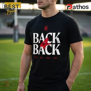 Black cotton t-shirt with white BACK 4 BACK text, red logo, and 2023-2026 dates on a blurred rugby field background.!