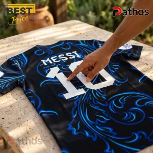 Black and blue soccer jersey with Messi 10 printed in white on the back, resting on a textured stone table.!