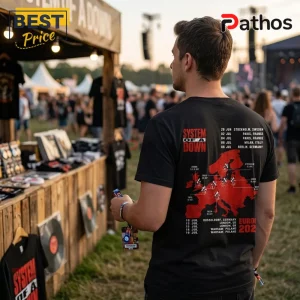Man wearing black System of a Down tour t-shirt with red Europe map graphic and concert dates at an outdoor festival.!