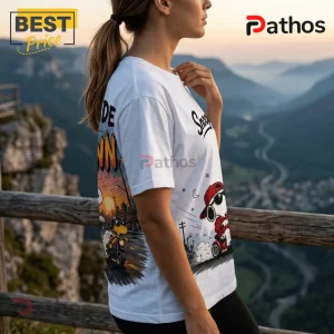 2026 Snoopy We Ride At Dawn Biker T-Shirt 3 White t-shirt featuring a cartoon Snoopy wearing a red cap and sunglasses while riding a motorcycle against city sunset.!