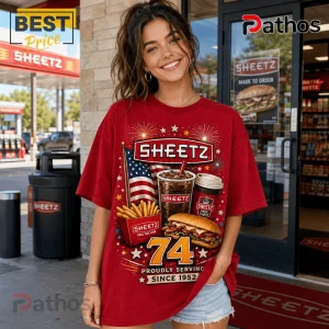 Sheetz 74th Anniversary 1952-2026 Red T-Shirt 3 Woman wearing a red oversized t-shirt with Sheetz brand graphics, fries, sub sandwich, coffee, and American flag print.!
