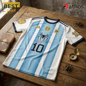 Messi x Spider-Man Argentina 2026 FIFA World Champion T-Shirt 1 Argentina national football jersey with Spider-Man web pattern and number 10 on a wooden table with compass and spiders.!