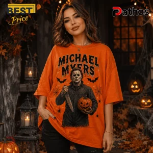 Michael Myers Halloween Orange T-Shirt 2026 3 Michael Myers Halloween Orange T-Shirt 2026 featuring a horror movie print, knife, pumpkin, and bats on orange fabric.