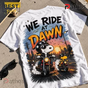 2026 Snoopy We Ride At Dawn Biker T-Shirt 4 White graphic t-shirt featuring Snoopy and Woodstock riding red motorcycles with the text We Ride At Dawn.!