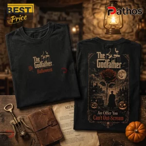 Black cotton t-shirts with The Godfather logo, rose, and pumpkin graphics on rustic table with lantern and leather book.!
