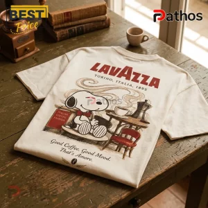Off-white t-shirt with Snoopy graphic, Lavazza logo, and Italian coffee theme illustration on a rustic wooden table.!