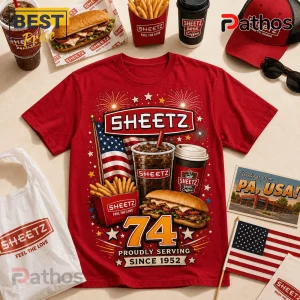 Sheetz 74th Anniversary 1952-2026 Red T-Shirt 1 Red graphic t-shirt featuring Sheetz logo, fries, soda, sandwich, American flag, and 1952 text on a flat surface.!