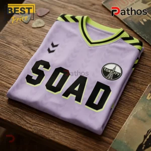 Lavender soccer-style jersey with SOAD text, Toxcity patch, neon yellow trim, and black chevron patterns on a wood surface.!