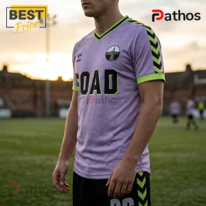 Man wearing a lavender v-neck soccer jersey with black Toxcity text, green trim, and chevron sleeve patterns on a field.!