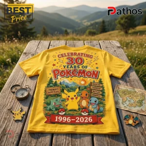 Pokémon 30th Anniversary Pikachu Yellow T-Shirt featuring graphic print of starters on a wooden table in a mountain landscape.