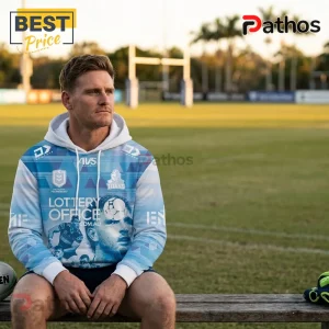 Gold Coast Titans Jai Arrow light blue hoodie with team logos and sponsor graphics worn by a male athlete on a rugby field.