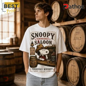 Snoopy Saloon Jack Daniel’s Tennessee Whiskey Shirt on a man in a distillery, featuring Snoopy in a cowboy hat and bar art.